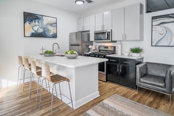 A modern kitchen with a white island and black appliances.